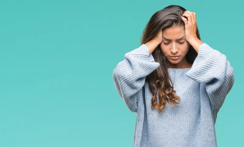 Woman holding her head in distress, symbolizing anxiety or PTSD symptoms.